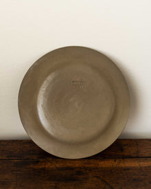 Brown ceramic plate on a wooden surface with a white background
