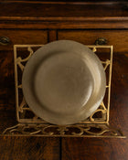 Ceramic plate on a decorative metal stand with wooden background