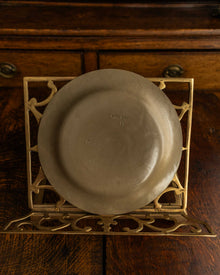 Ceramic plate on a decorative metal stand with wooden background