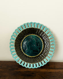Decorative ceramic plate with turquoise rim and black interior on a wooden surface.