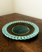 Ceramic plate with turquoise rim and dark center on a wooden surface