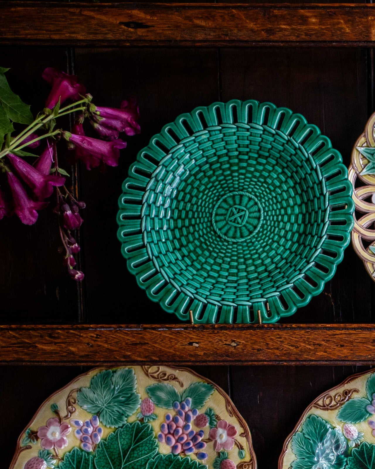 Green green woven plate on a wooden surface with floral decorations in the background