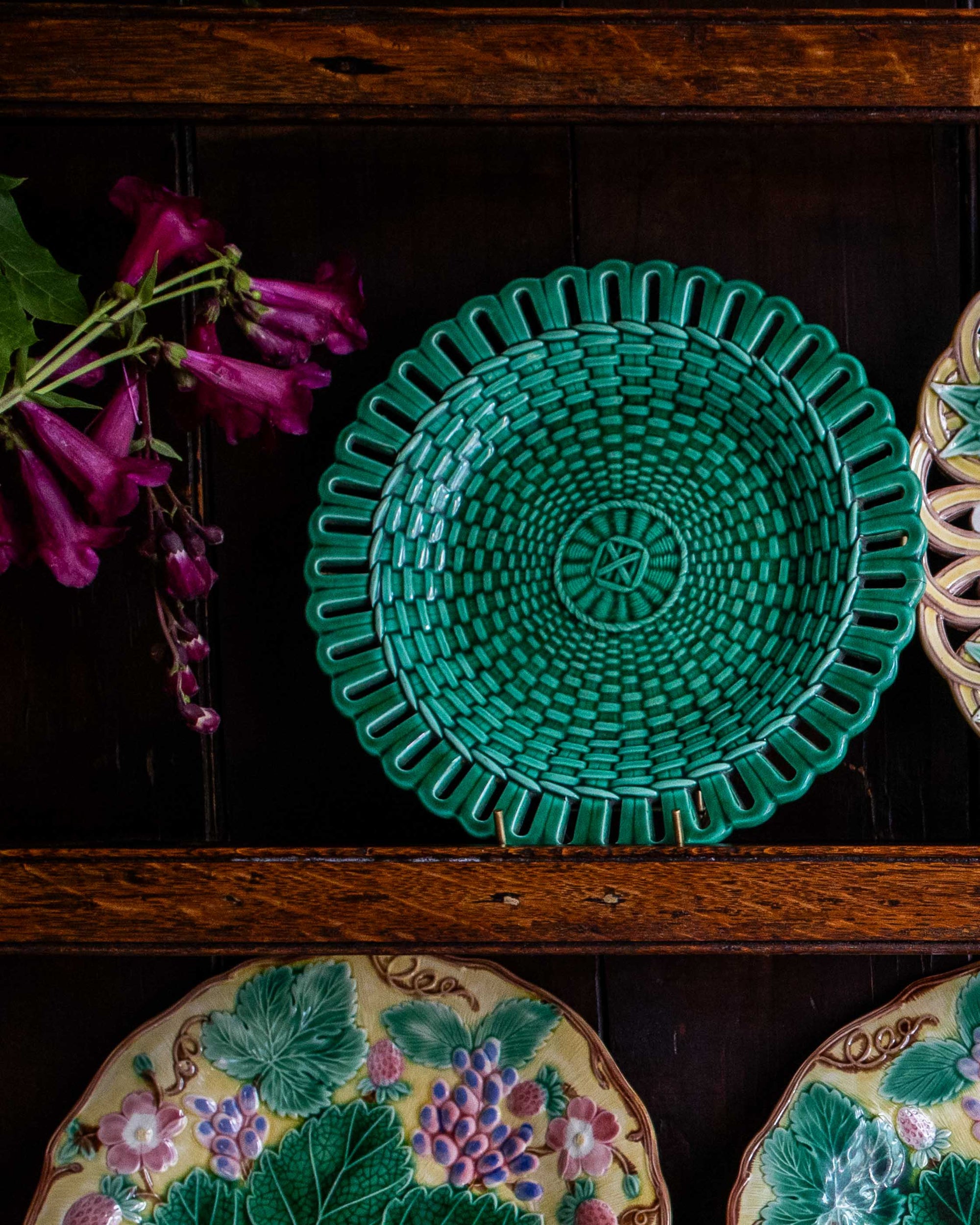 Green green woven plate on a wooden surface with floral decorations in the background
