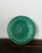 Green woven plate on a wooden surface with a white background
