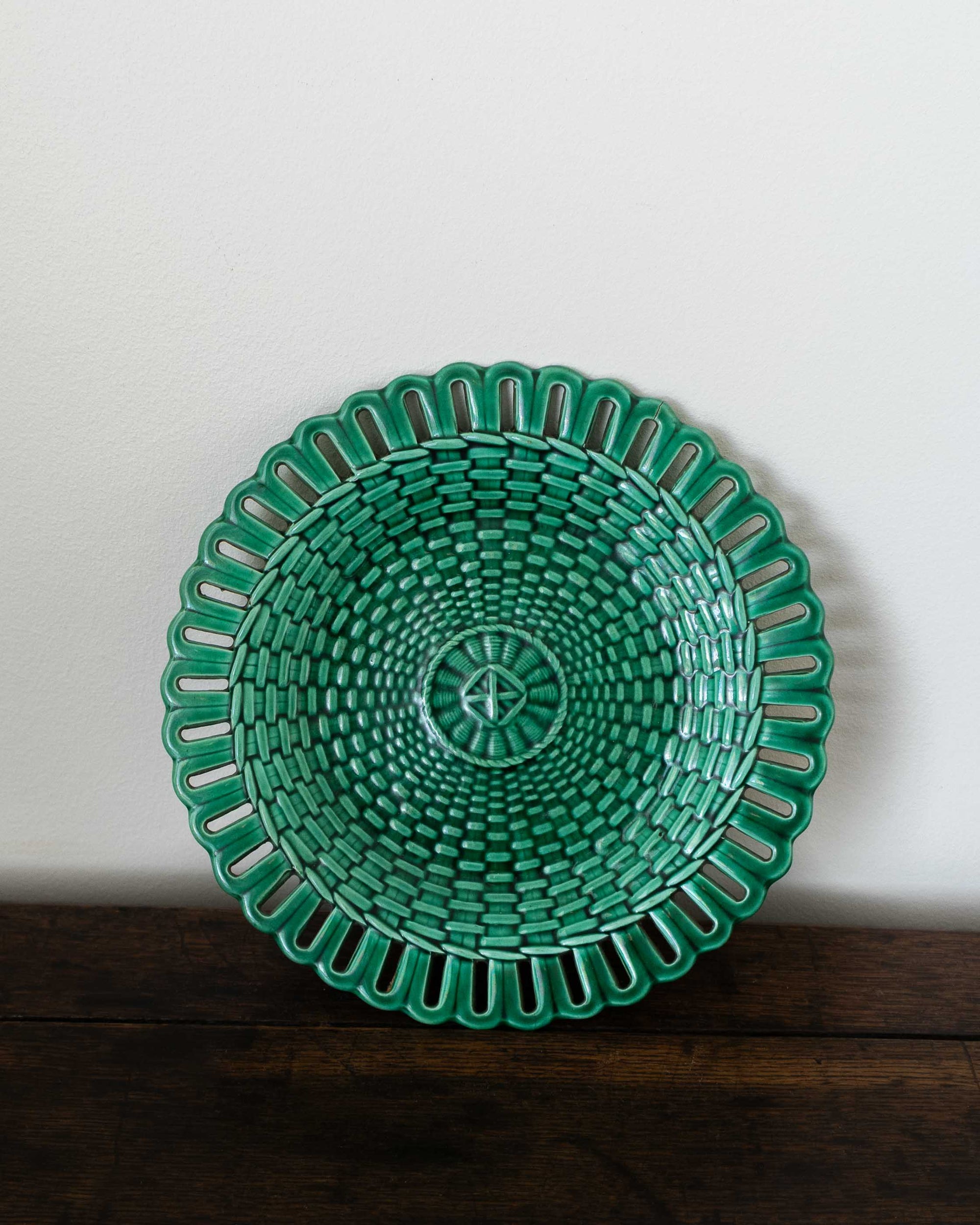Green woven plate on a wooden surface with a white background
