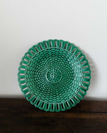Green woven plate on a wooden surface with a white background