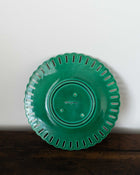 Green ceramic plate with decorative edge on a white background