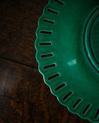 Close-up of a green ceramic plate with decorative edge on a wooden surface
