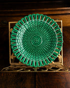 Green woven plate on a decorative stand with a wooden background