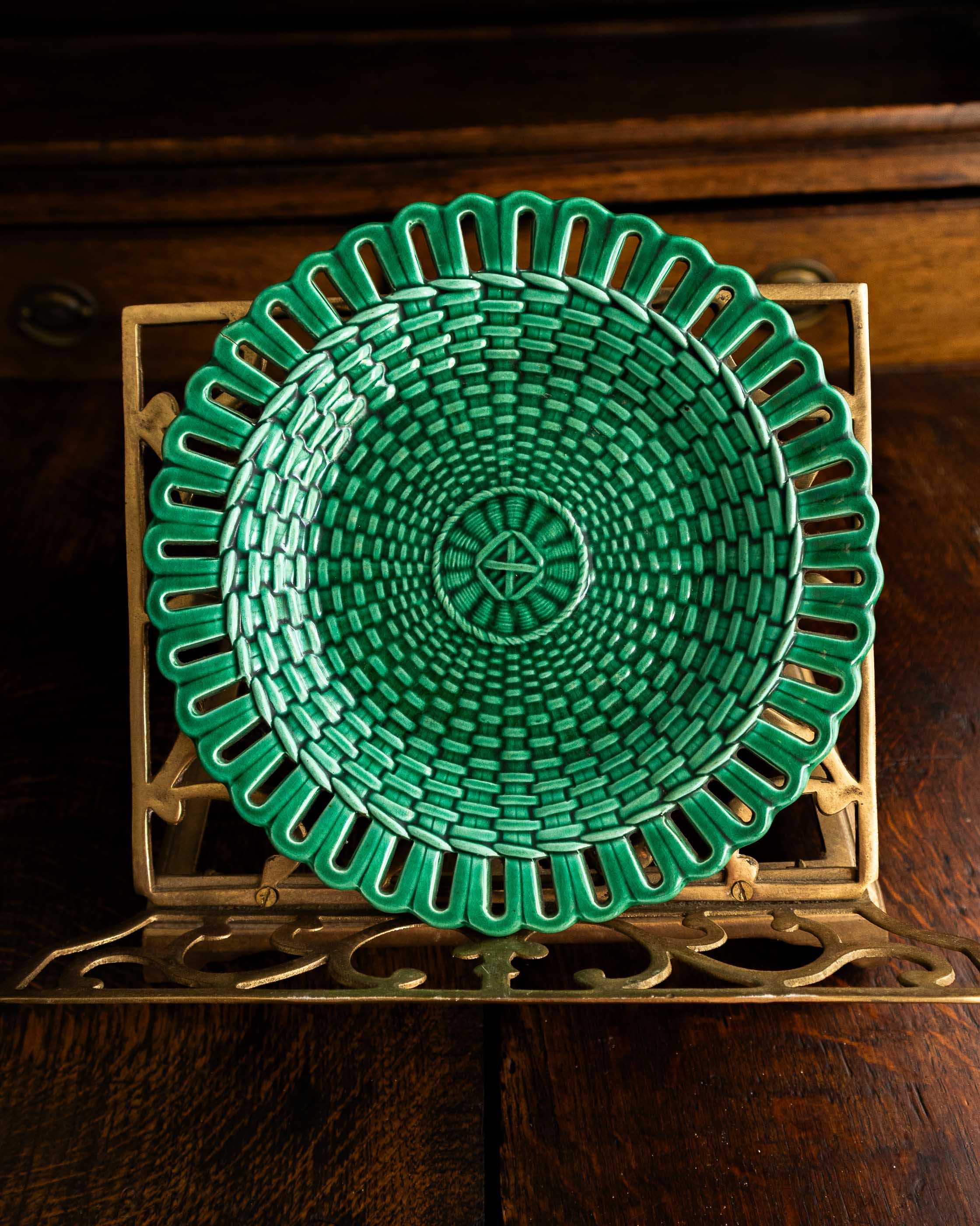 Green woven plate on a decorative stand with a wooden background