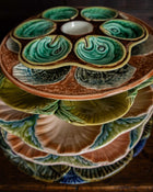 Stack of ceramic majolica plates with shell design on a wooden surface