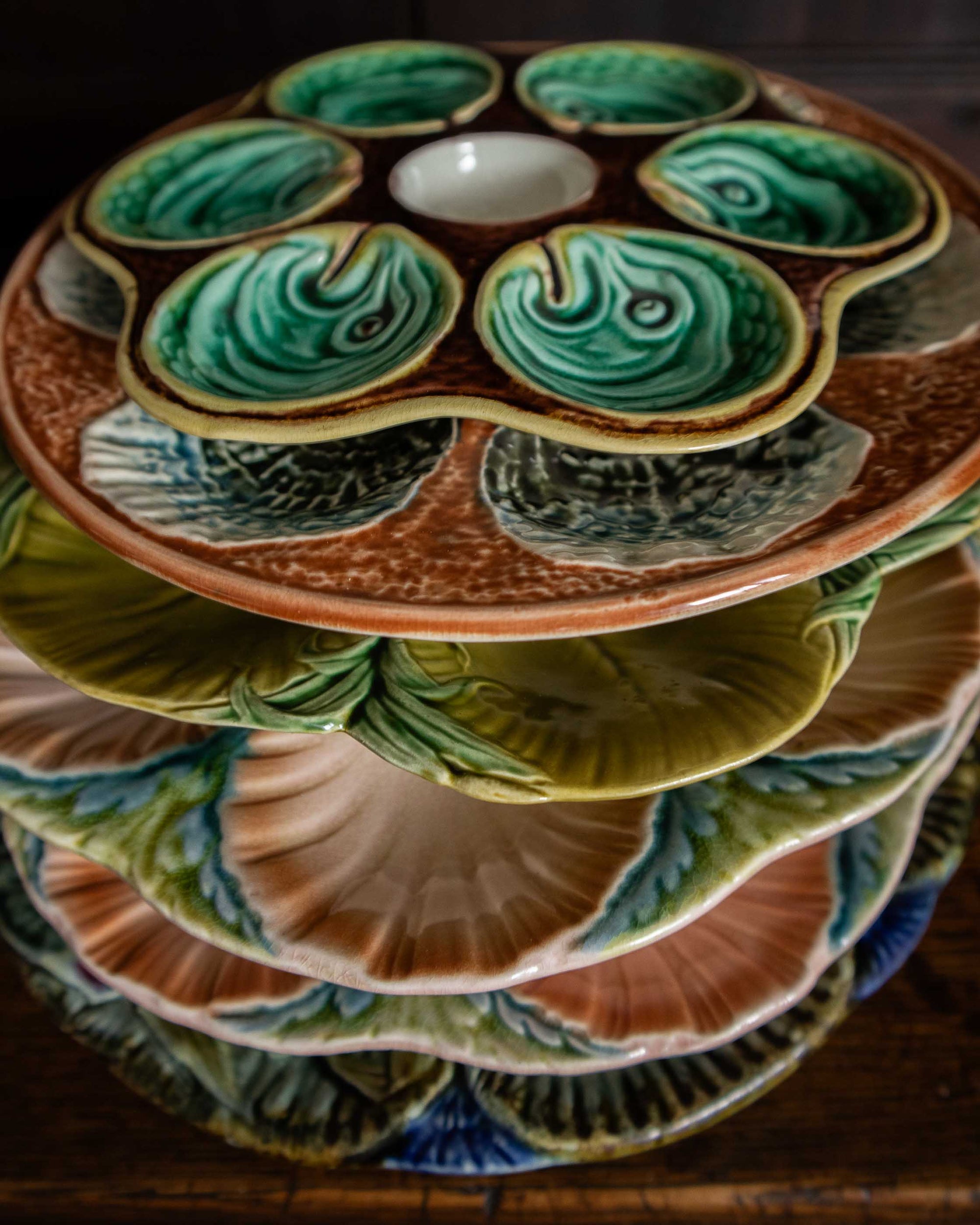 Stack of ceramic majolica plates with shell design on a wooden surface