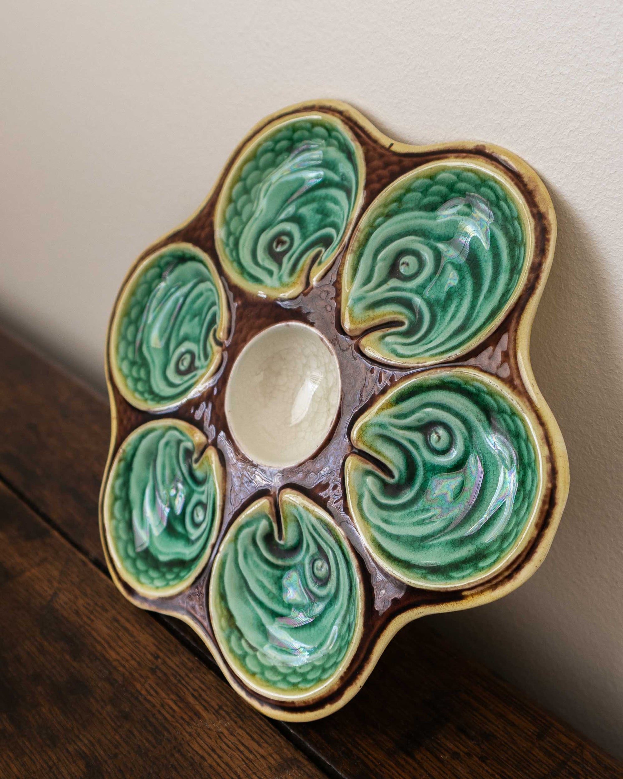 Ceramic oyster plate with green shell design on a wooden surface
