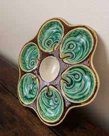 Ceramic oyster plate with green shell design on a wooden surface
