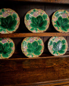 Set of ceramic plates with leaf design on a wooden shelf