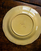 Yellow ceramic plate with 'Wedgwood' branding on a wooden surface