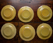 Six yellow ceramic plates on a wooden surface