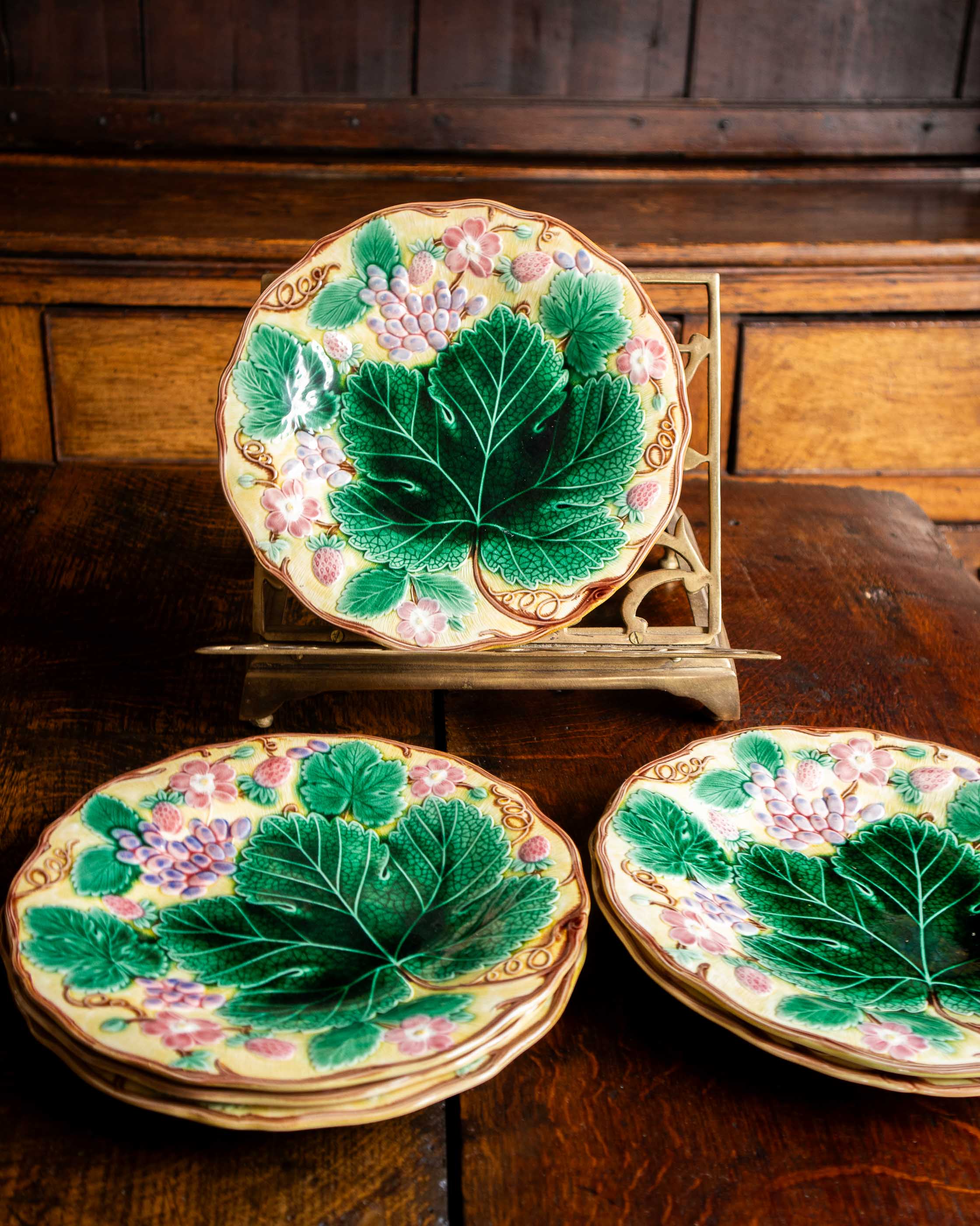 Three decorative ceramic plates with green leaf designs on a wooden surface.