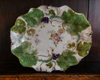Decorative ceramic plate with floral and leaf patterns on a wooden surface