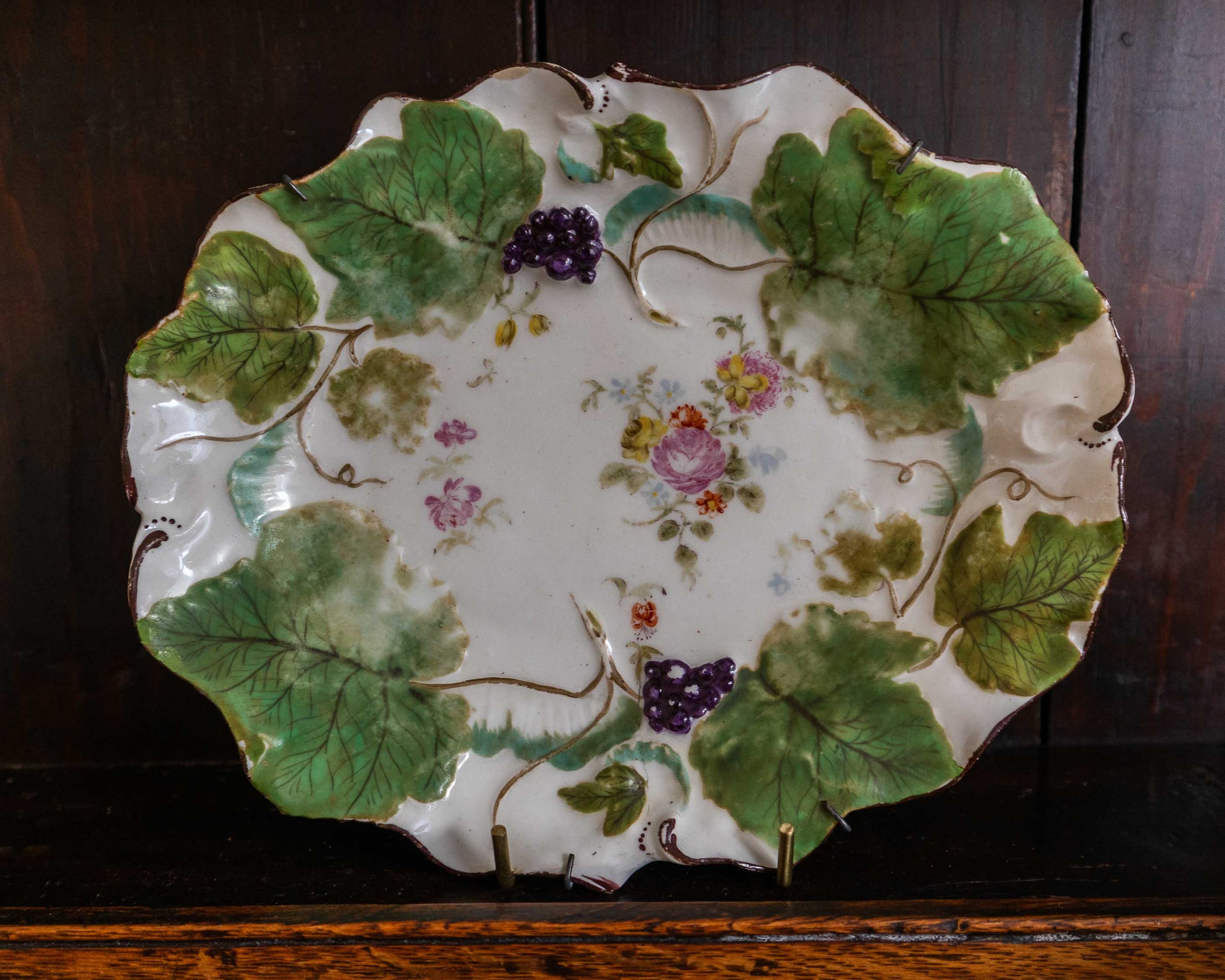 Decorative ceramic plate with floral and leaf patterns on a wooden surface