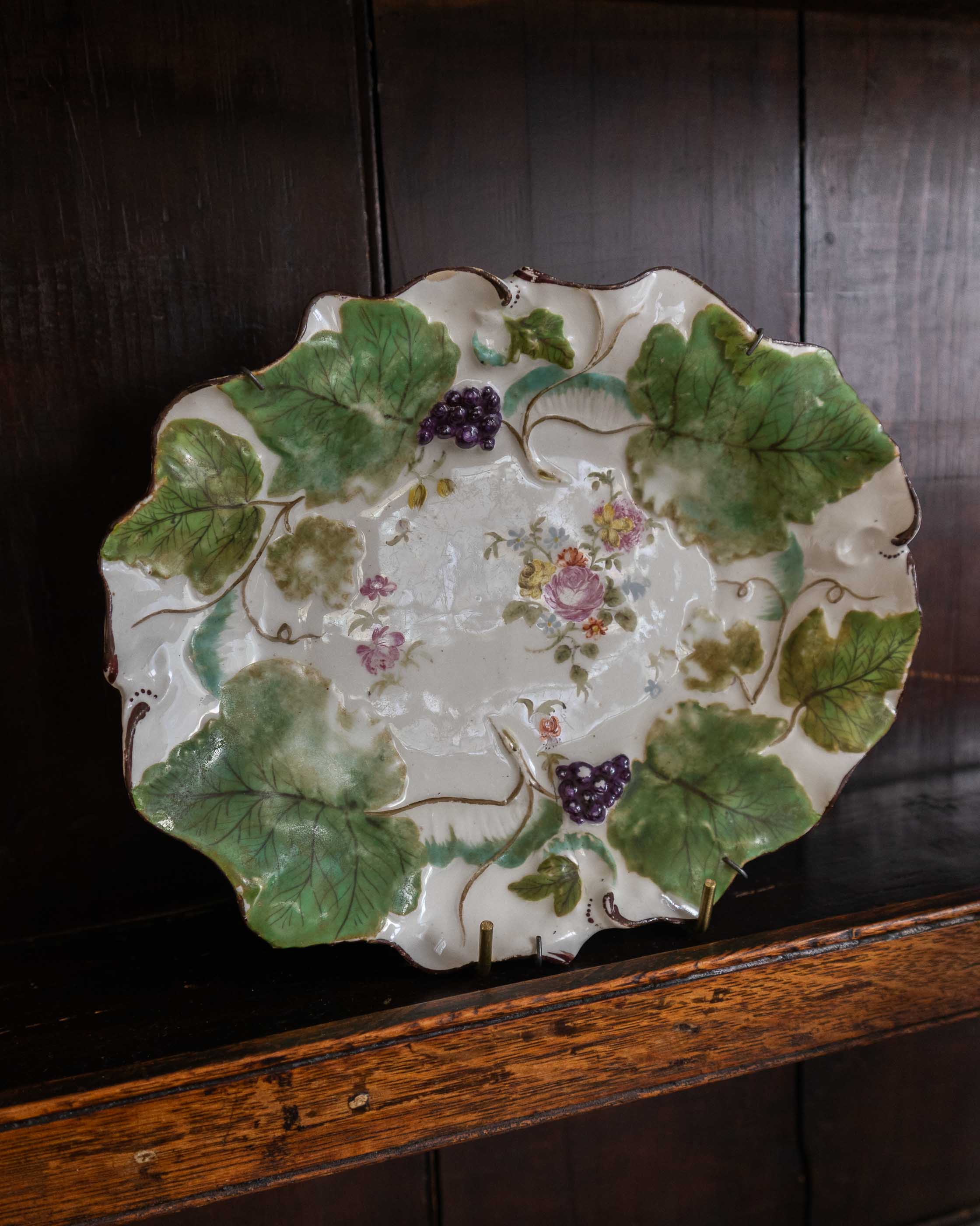 Decorative ceramic plate with floral and leaf design on a wooden surface