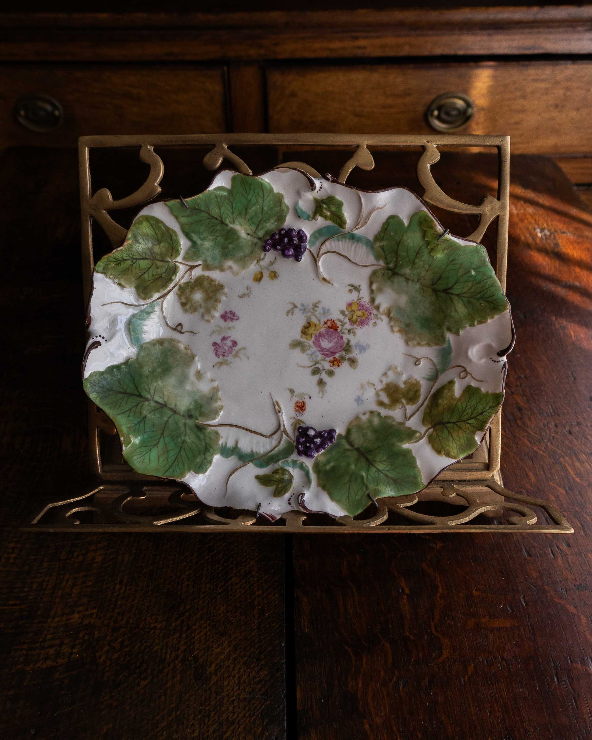 Decorative plate with floral and leaf design on a wooden surface