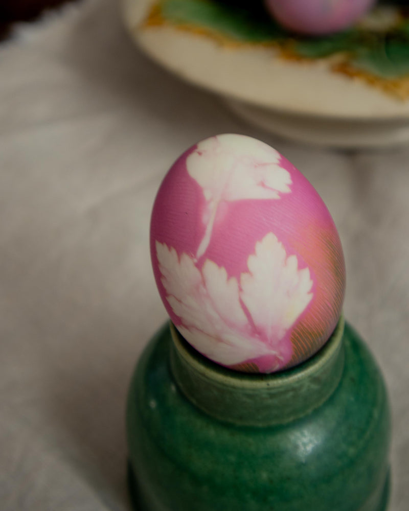 Decorative red Easter egg with floral design on a green jar