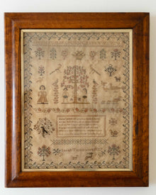 Framed sampler with intricate patterns and text on a white background