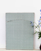 Patterned wall art piece on a white wall with a vase of flowers to the right.
