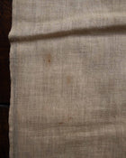 Close-up of beige fabric with a dark stain on a wooden surface
