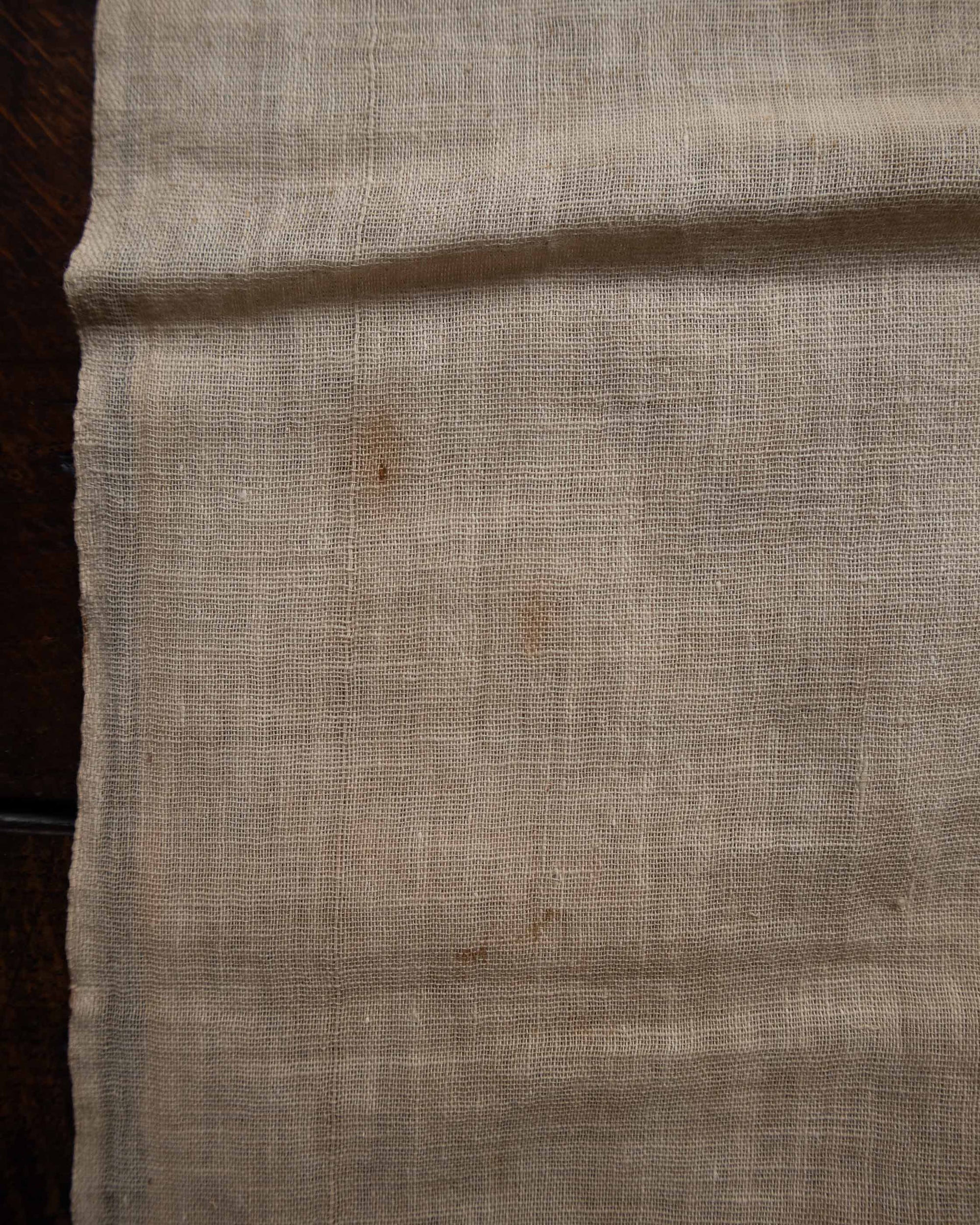 Close-up of beige fabric with a dark stain on a wooden surface