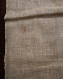 Close-up of beige fabric with a dark stain on a wooden surface