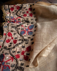Close-up of embroidered fabric with red and blue floral patterns on a beige background