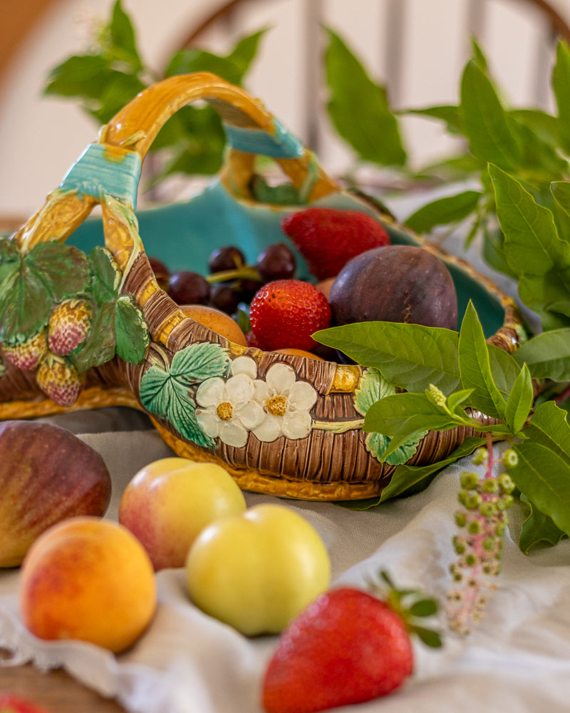 Majolica basket with fruits and berries on a table with greenery