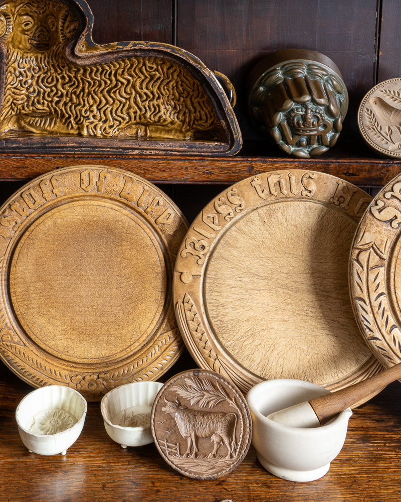 Wooden breadboards with carved designs on a wooden shelf.