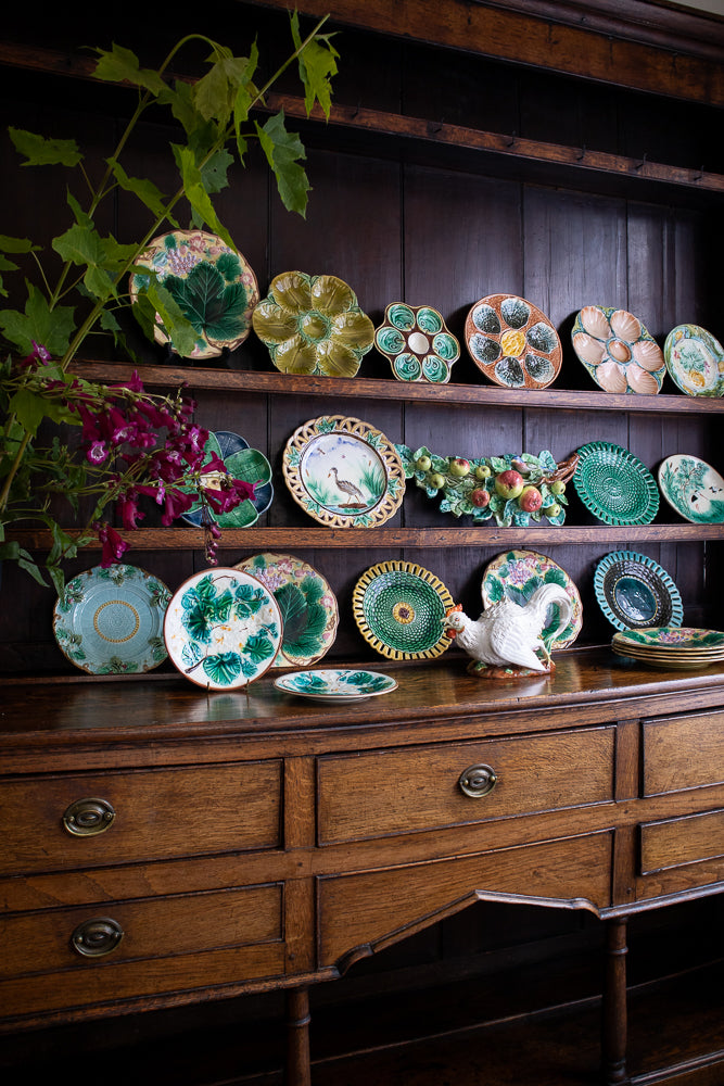 Collection of decorative plates on a wooden dresser with a dark background