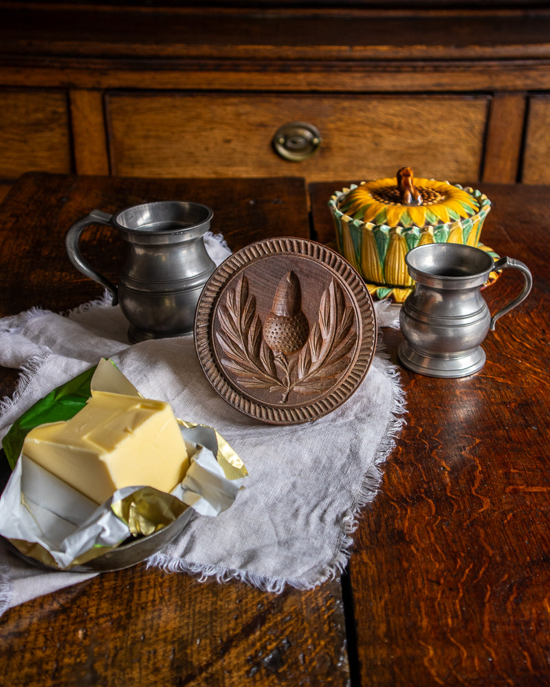 Wooden butter patting block with two metal containers on a wooden surface.