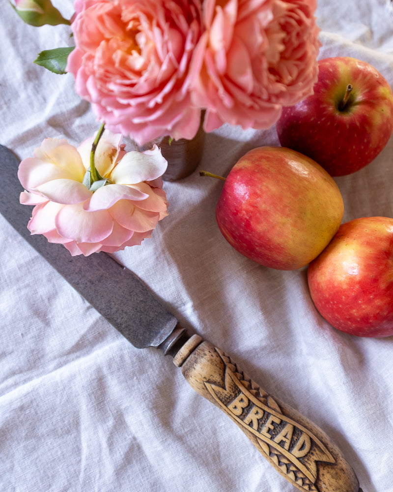 Antique breadknife with roses and apples on a light cloth