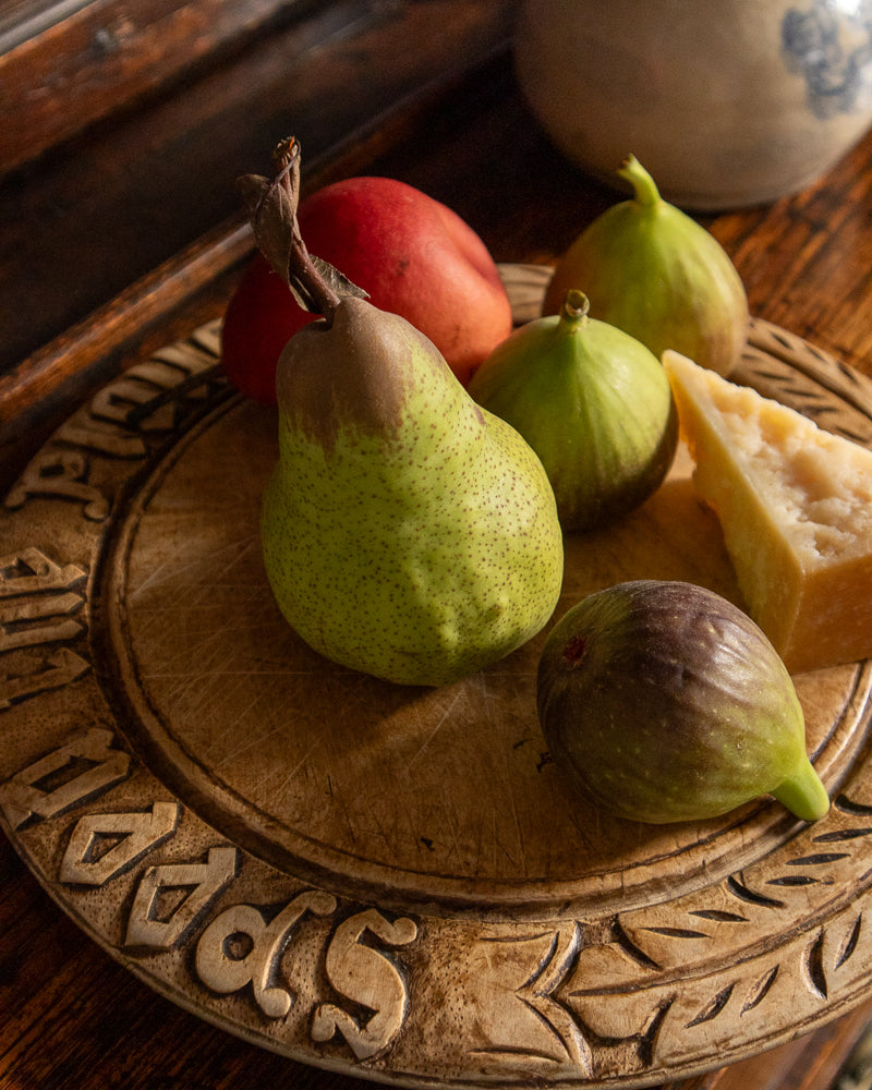 Pears and figs on a decorative wooden breadboard with a rustic background