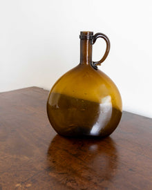 Brown glass jug on a wooden surface with a white background