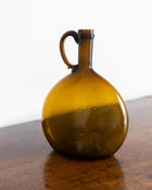 Brown glass jug on a wooden surface with a white background