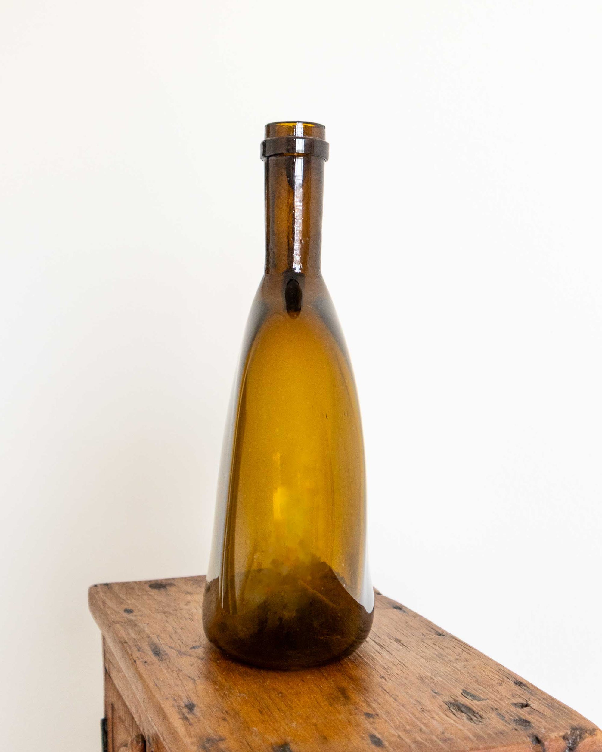 Brown glass flagon on a wooden surface with a white background