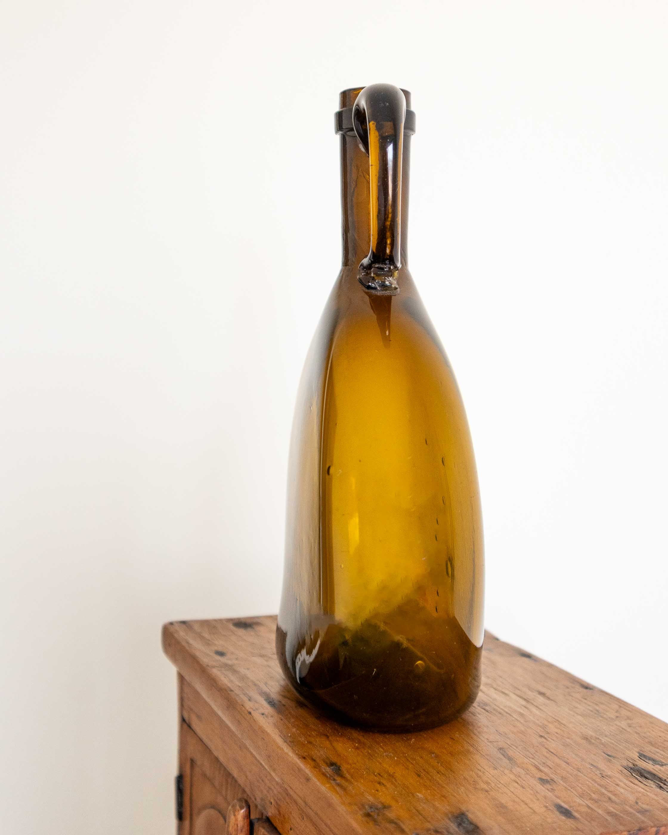 Brown glass flagon on a wooden surface with a white background