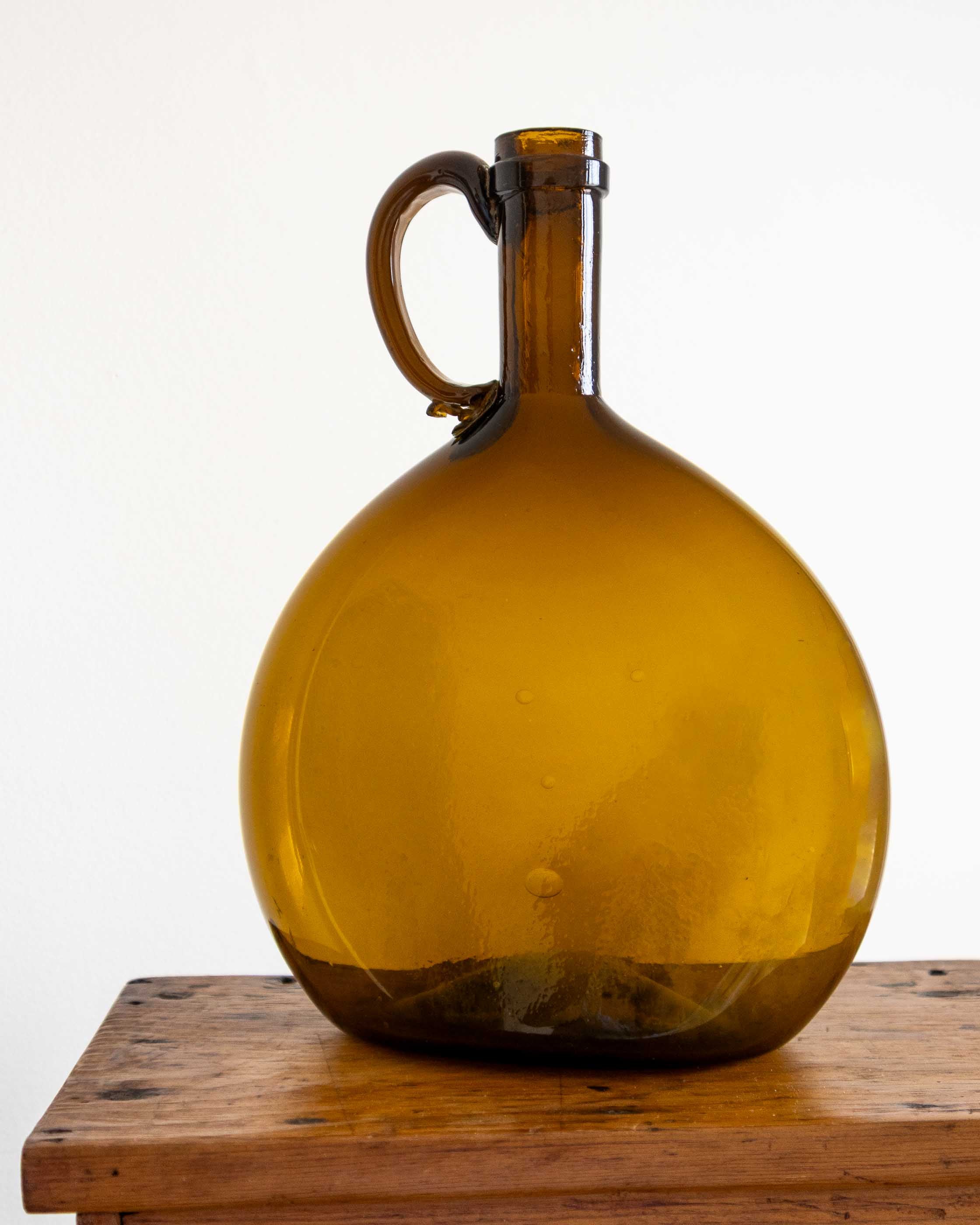 Amber glass jug on a wooden surface with a white background