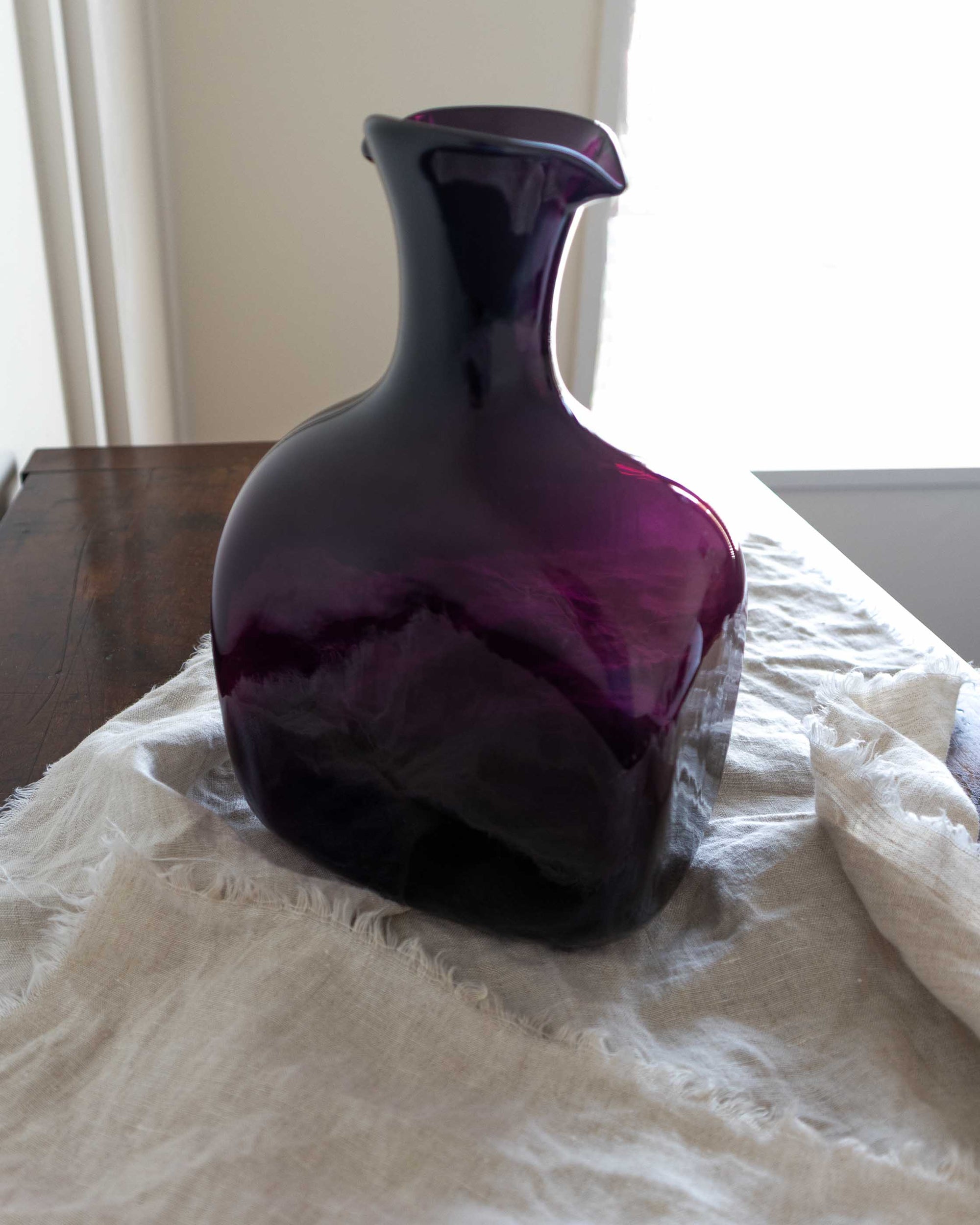 Amethyst glass decanter on a textured surface with a neutral background