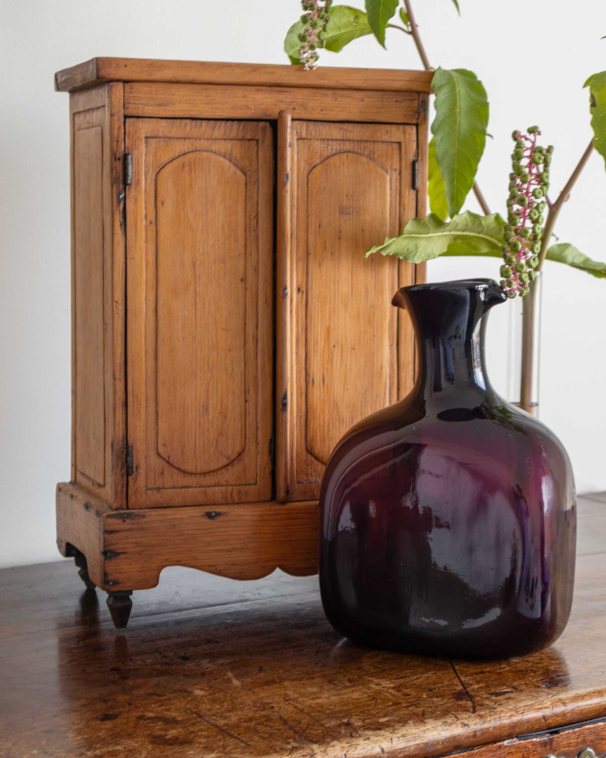 Vintage wooden cabinet with a dark purple decanter on a wooden surface