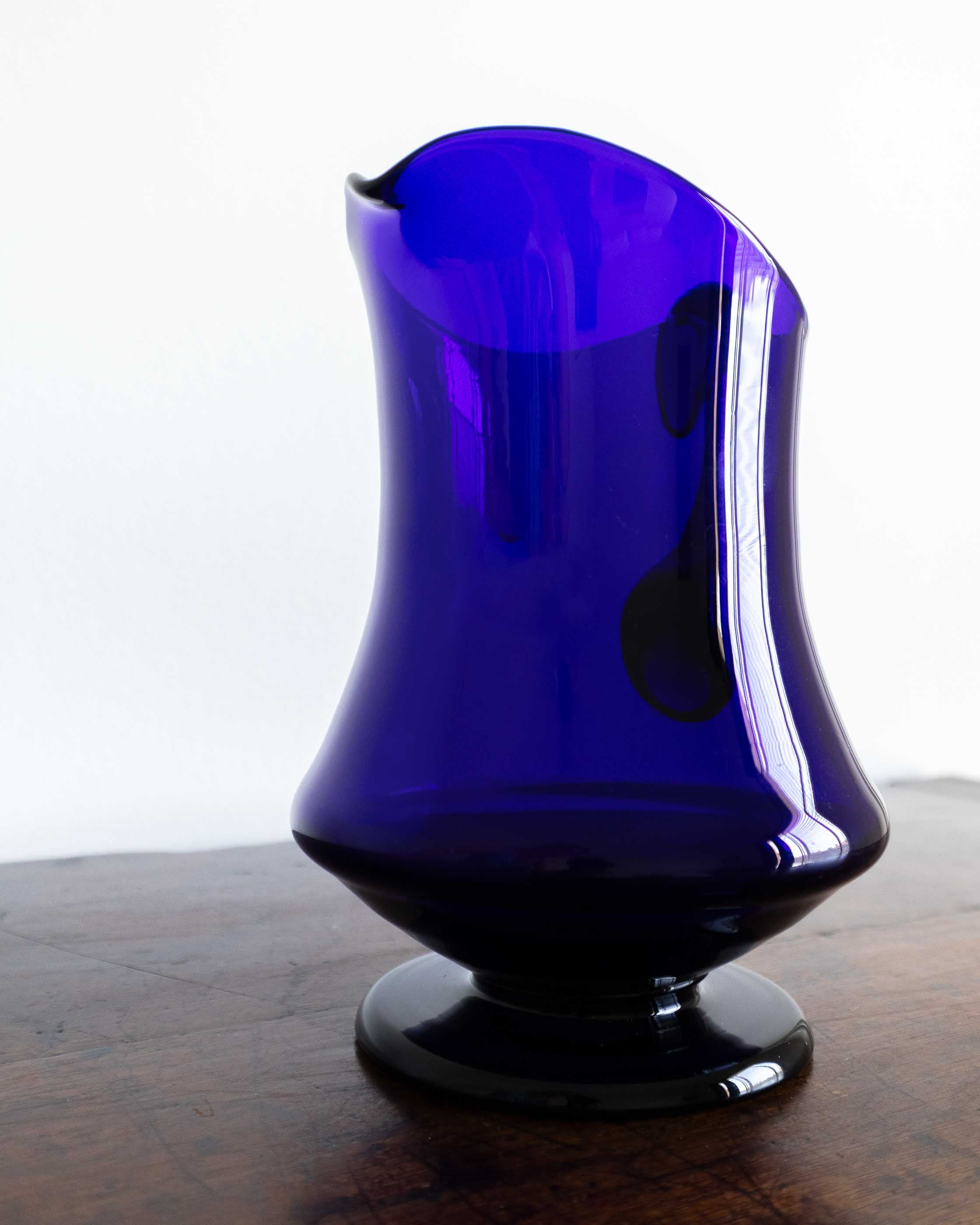 Blue glass vase on a wooden surface with a white background