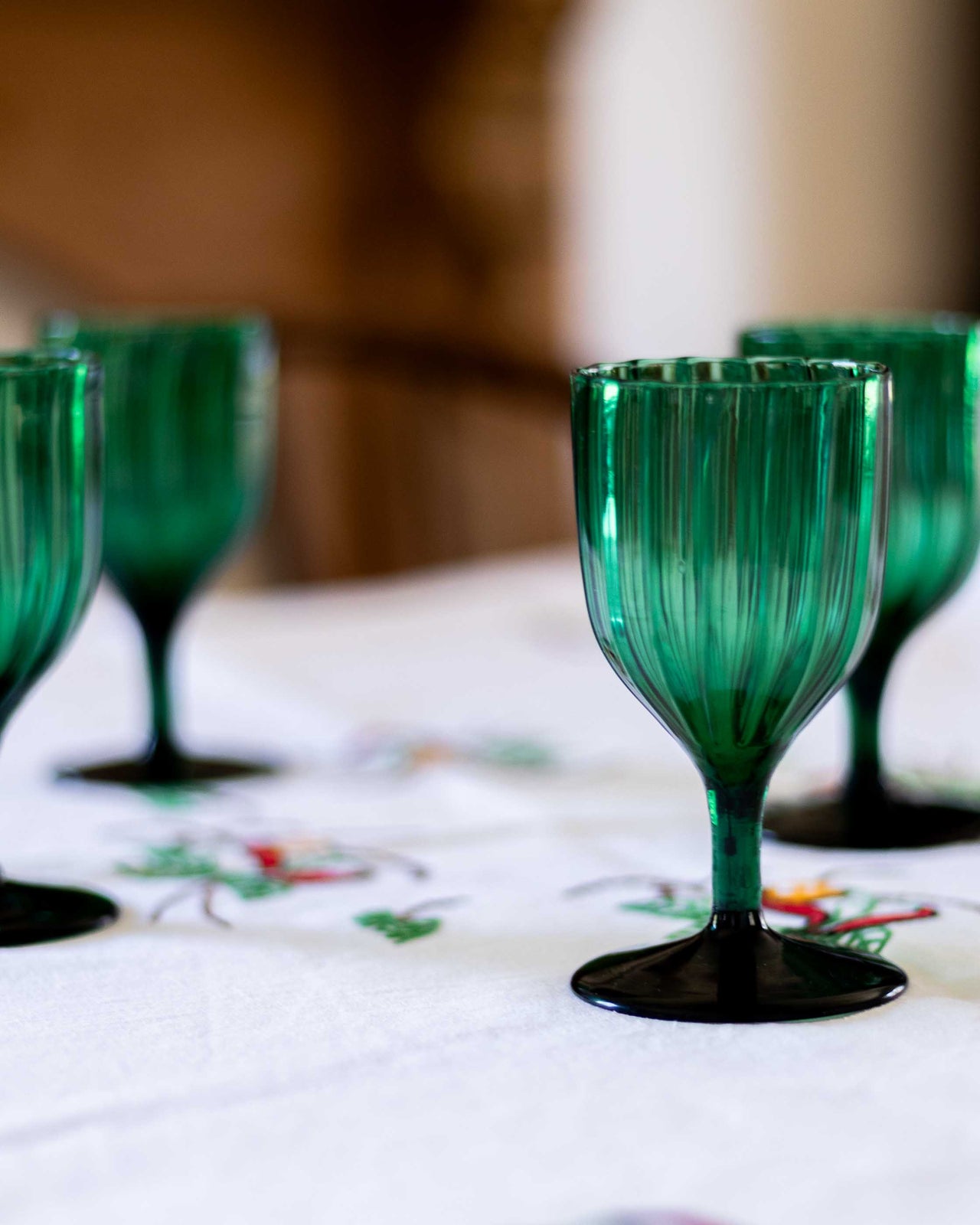 Green glass goblets on a table with a blurred background