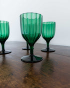 Green glass goblets on a wooden surface with a blurred background