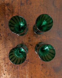 Four green glasses on a wooden surface